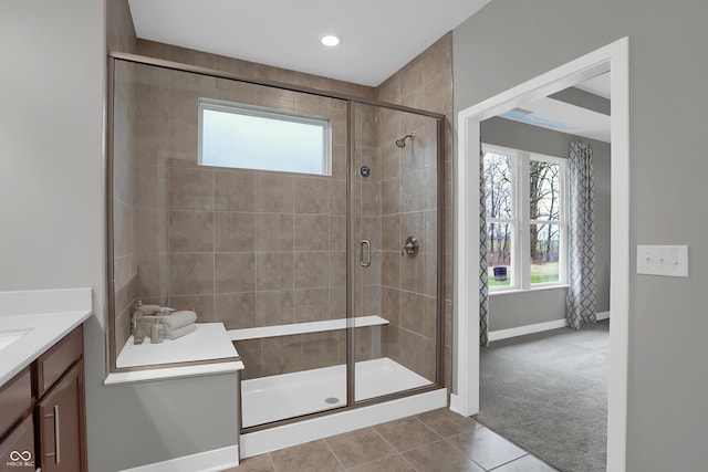 bathroom featuring tile patterned flooring, baseboards, a shower stall, and vanity