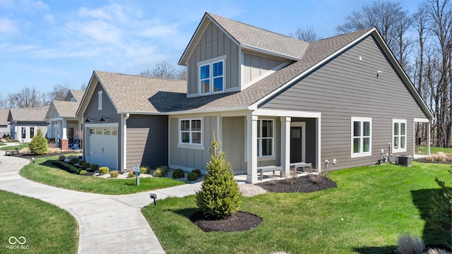 exterior space featuring roof with shingles, a yard, an attached garage, board and batten siding, and central AC