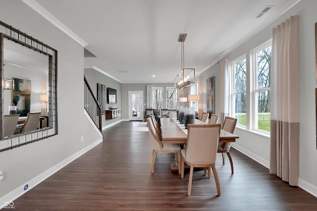 dining room featuring dark wood finished floors, crown molding, a notable chandelier, visible vents, and baseboards