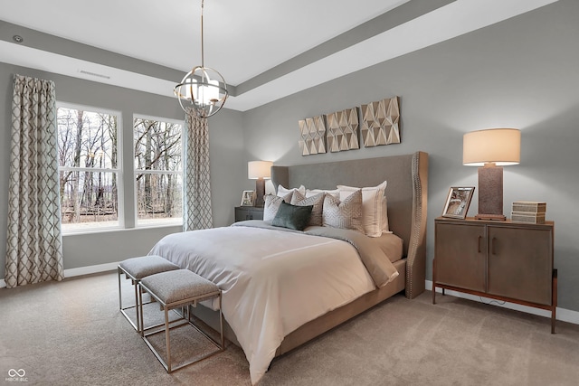 carpeted bedroom featuring a chandelier, a tray ceiling, visible vents, and baseboards