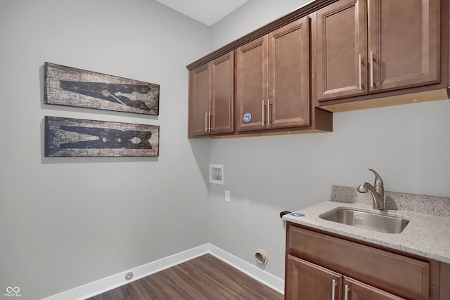 washroom featuring cabinet space, baseboards, dark wood-style flooring, washer hookup, and a sink