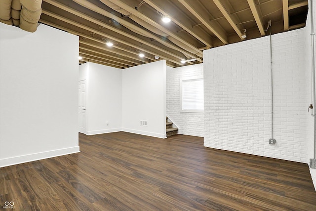 basement featuring brick wall and dark hardwood / wood-style floors