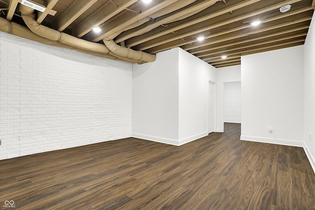 basement with brick wall and dark hardwood / wood-style floors