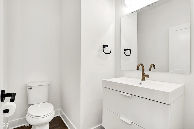 bathroom with toilet, hardwood / wood-style floors, and vanity