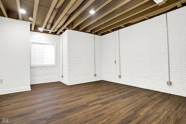 basement featuring brick wall and dark hardwood / wood-style floors