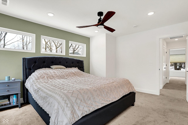 bedroom with ceiling fan, light colored carpet, and multiple windows