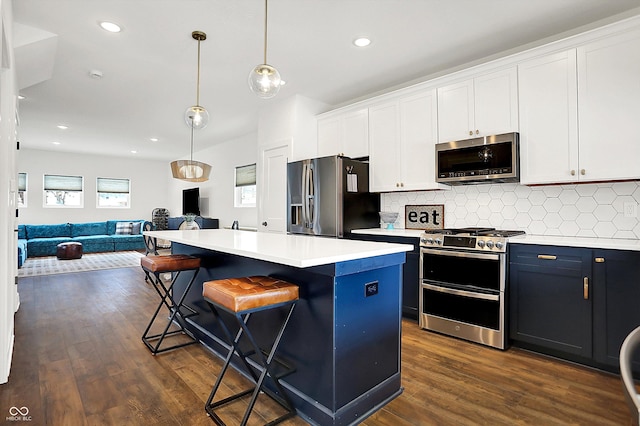 kitchen featuring stainless steel appliances, white cabinets, a center island, a kitchen breakfast bar, and pendant lighting