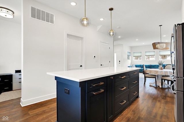 kitchen with a kitchen island, stainless steel refrigerator, pendant lighting, and dark hardwood / wood-style floors