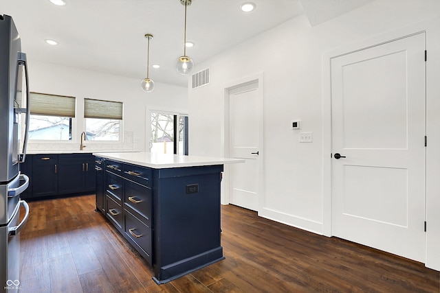 kitchen featuring decorative light fixtures, a kitchen island, stainless steel fridge, and dark hardwood / wood-style floors