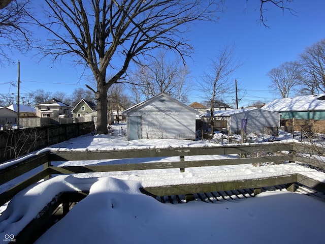 yard layered in snow with a garage and an outdoor structure