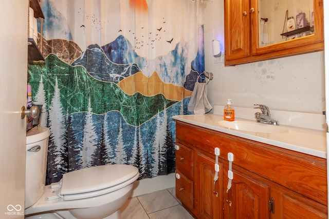 bathroom with toilet, vanity, and tile patterned flooring