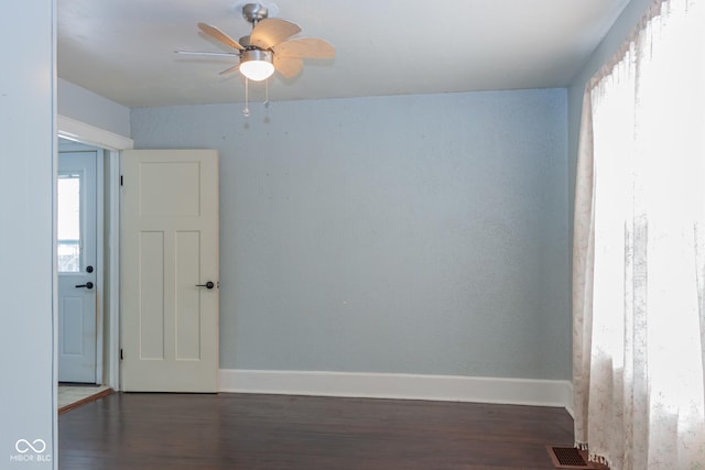 unfurnished room with ceiling fan, a wealth of natural light, and dark hardwood / wood-style flooring