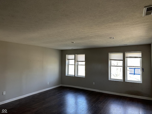 spare room featuring plenty of natural light, dark hardwood / wood-style flooring, and a textured ceiling