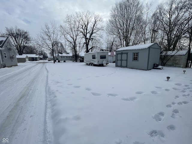 snowy yard featuring a storage unit