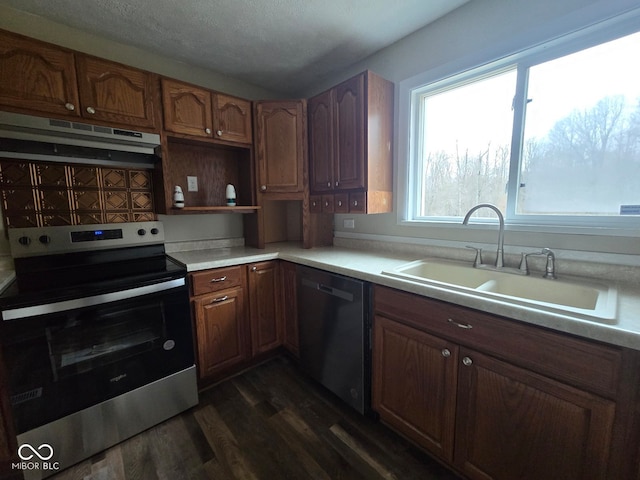 kitchen with appliances with stainless steel finishes, dark hardwood / wood-style flooring, tasteful backsplash, a textured ceiling, and sink