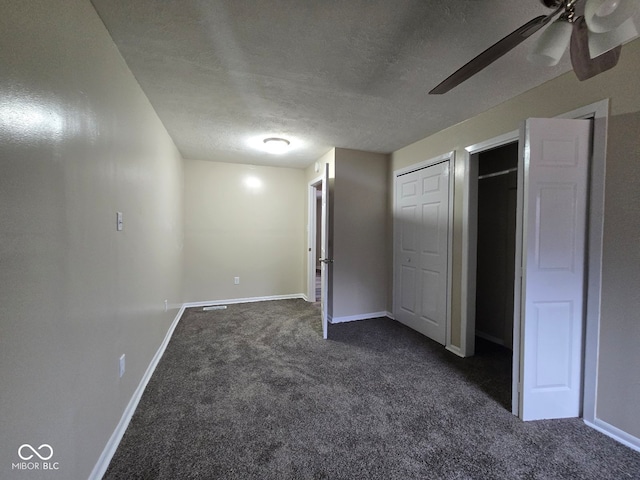 unfurnished bedroom featuring dark colored carpet, a textured ceiling, and ceiling fan