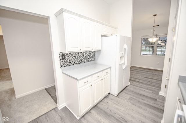 kitchen featuring white refrigerator with ice dispenser, pendant lighting, light hardwood / wood-style floors, tasteful backsplash, and white cabinets