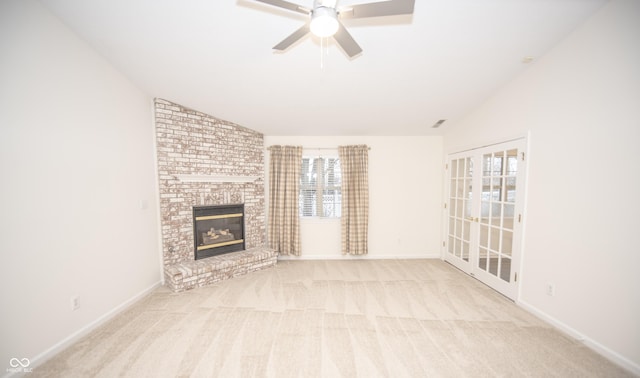 unfurnished living room with lofted ceiling, a brick fireplace, light carpet, and ceiling fan