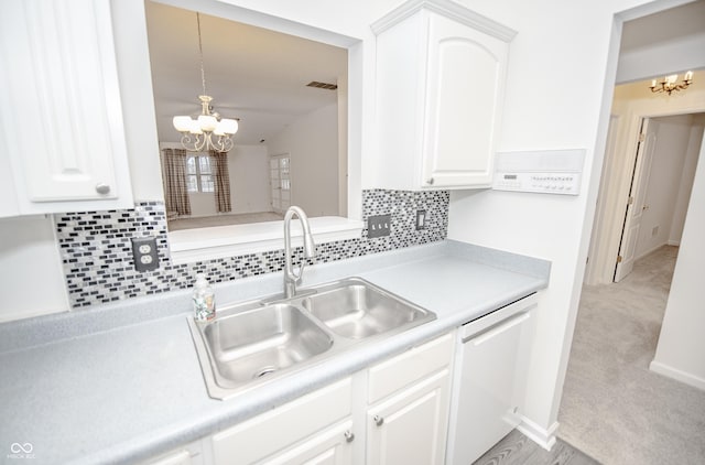 kitchen featuring white dishwasher, white cabinets, and a notable chandelier