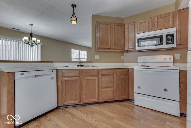 kitchen featuring sink, white appliances, light hardwood / wood-style floors, a textured ceiling, and decorative light fixtures