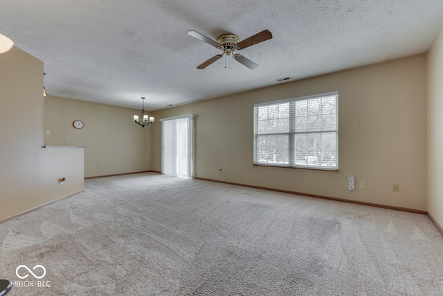 carpeted spare room featuring ceiling fan with notable chandelier and a textured ceiling