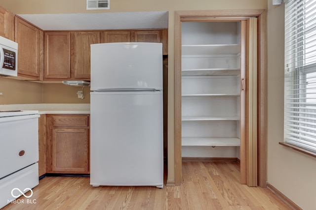 kitchen featuring a healthy amount of sunlight, white appliances, and light wood-type flooring