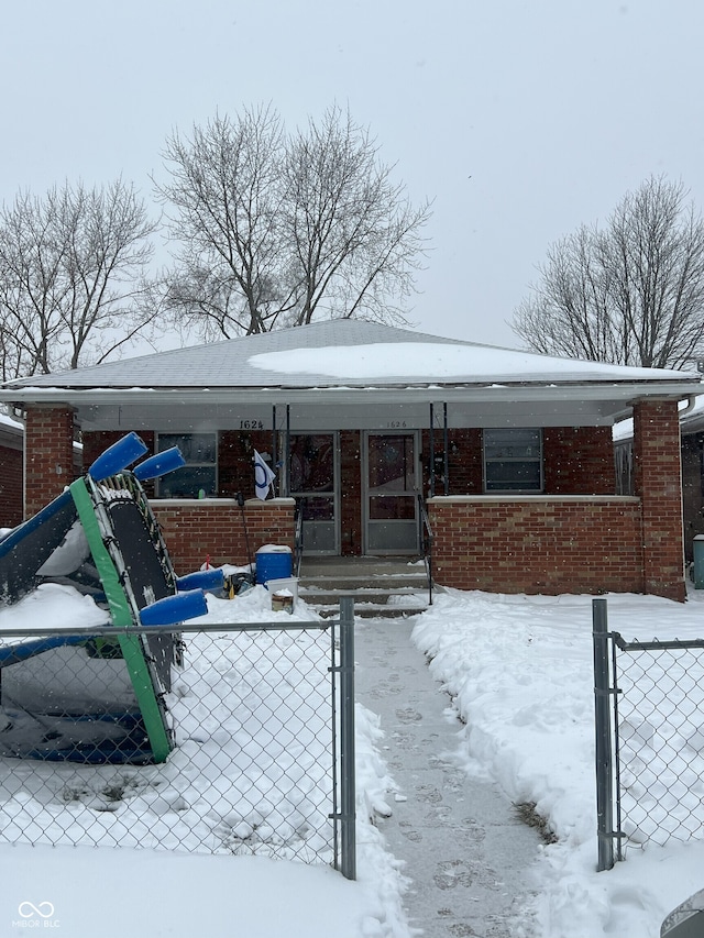 snow covered back of property featuring covered porch