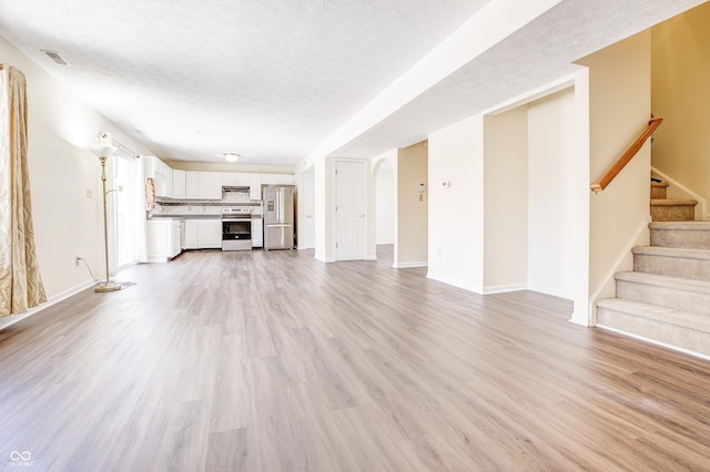 unfurnished living room with a textured ceiling and light hardwood / wood-style flooring