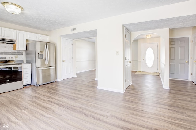 kitchen with a textured ceiling, light hardwood / wood-style flooring, stainless steel appliances, tasteful backsplash, and white cabinets