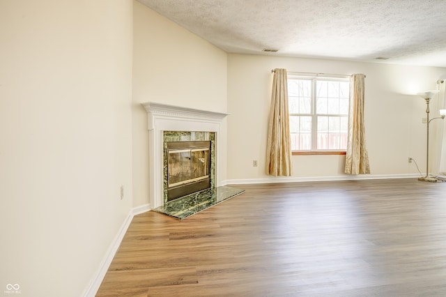 unfurnished living room with a textured ceiling, a fireplace, and hardwood / wood-style flooring