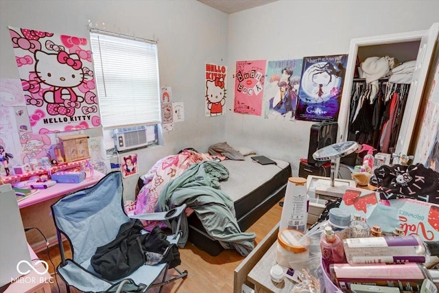 bedroom with cooling unit, light hardwood / wood-style floors, and a closet