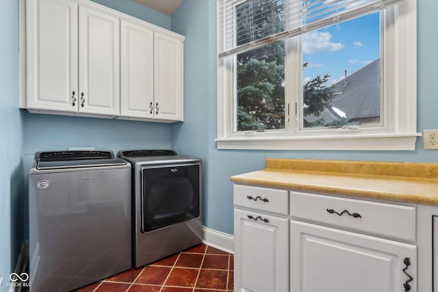 clothes washing area with separate washer and dryer, cabinets, and dark tile patterned floors