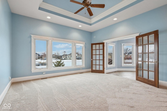 spare room featuring a tray ceiling, a wealth of natural light, ornamental molding, and french doors