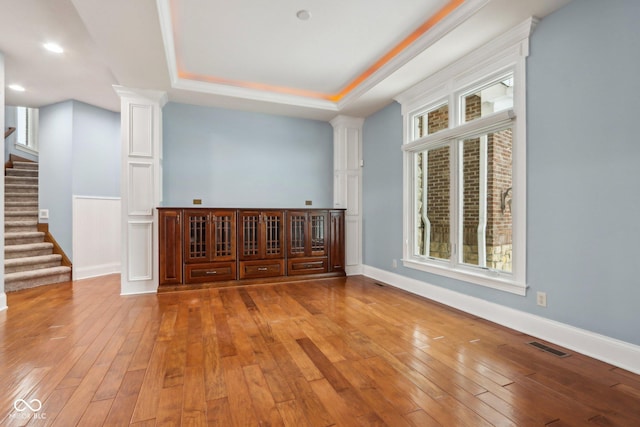 spare room with a raised ceiling and light hardwood / wood-style flooring