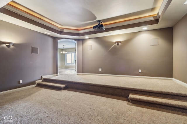 home theater room featuring ornamental molding, carpet flooring, and a raised ceiling