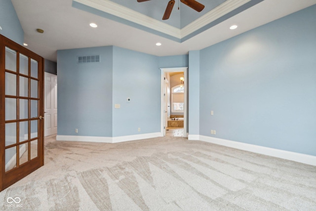 unfurnished room with a tray ceiling, ornamental molding, light colored carpet, and ceiling fan