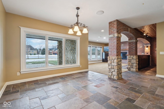 unfurnished dining area with a brick fireplace and ornate columns