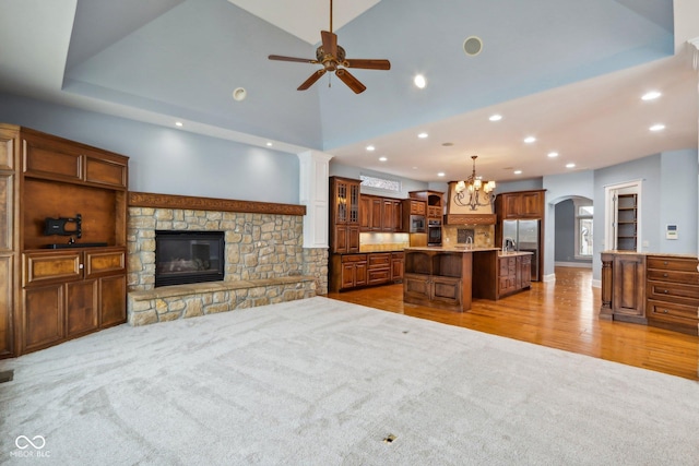 living room featuring high vaulted ceiling, a stone fireplace, light carpet, and ceiling fan