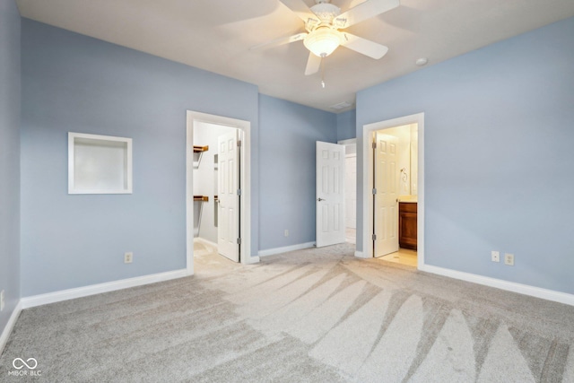 unfurnished bedroom with a walk in closet, ceiling fan, light carpet, ensuite bath, and a closet