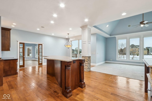 kitchen with a kitchen island, light hardwood / wood-style floors, decorative columns, and hanging light fixtures