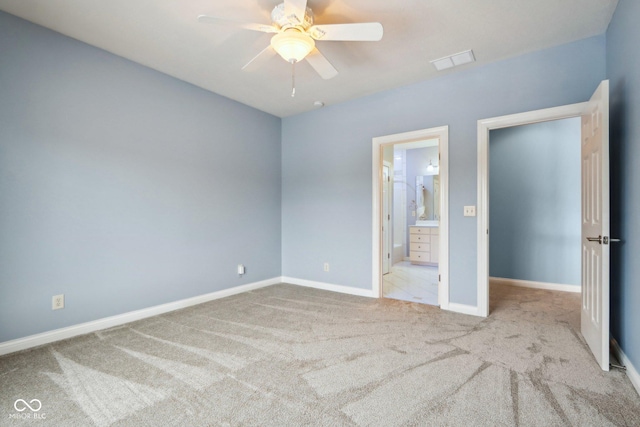 unfurnished bedroom featuring ceiling fan, ensuite bathroom, and light colored carpet