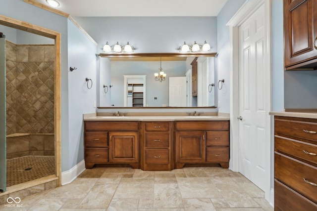 bathroom with vanity, a chandelier, and a tile shower