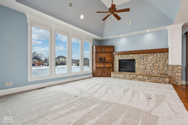 unfurnished living room featuring ceiling fan, a fireplace, high vaulted ceiling, and ornate columns