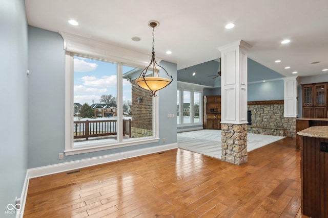 unfurnished dining area featuring ceiling fan, decorative columns, and light wood-type flooring