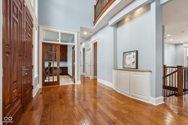 foyer entrance featuring a high ceiling and wood-type flooring