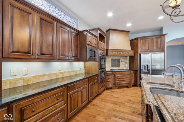 kitchen featuring premium range hood, tasteful backsplash, sink, dark stone counters, and stainless steel appliances