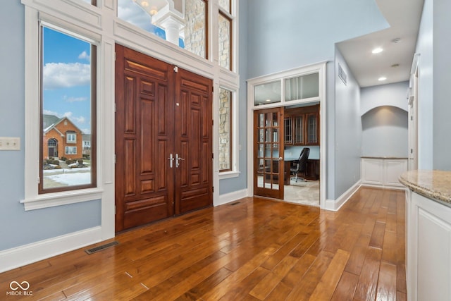 entryway with hardwood / wood-style flooring, a towering ceiling, and a wealth of natural light