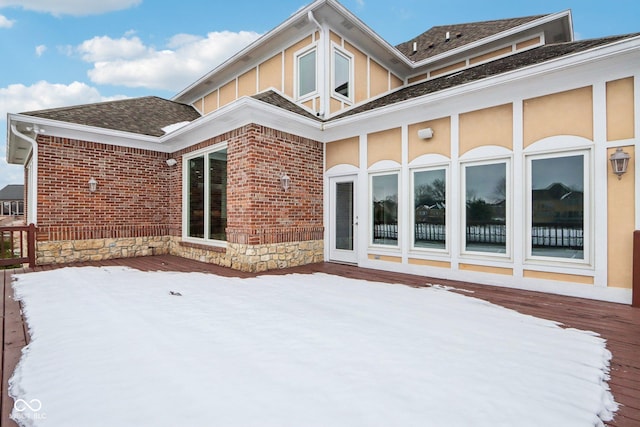 snow covered house with a wooden deck