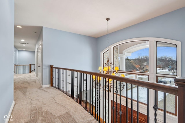 corridor featuring a notable chandelier, a wealth of natural light, and carpet