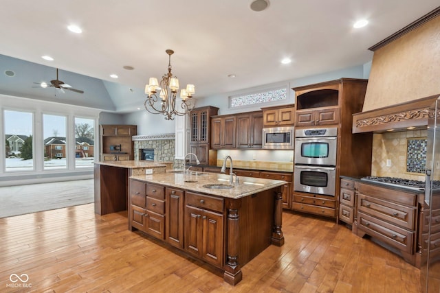 kitchen with a spacious island, appliances with stainless steel finishes, decorative light fixtures, and sink